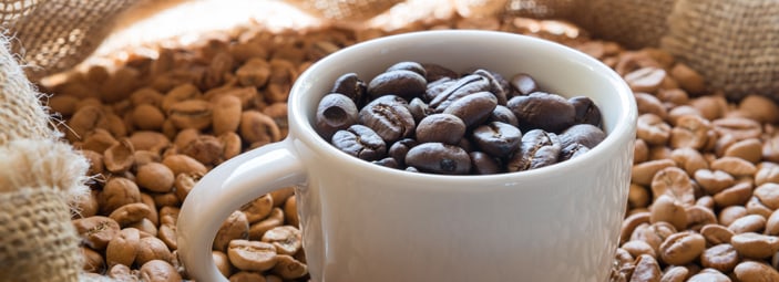 dettaglio di una tazzina colma di chicchi di caffè